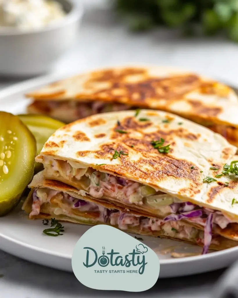 Crispy Reuben Quesadilla slices served with a side of dill pickles and a small scoop of coleslaw.