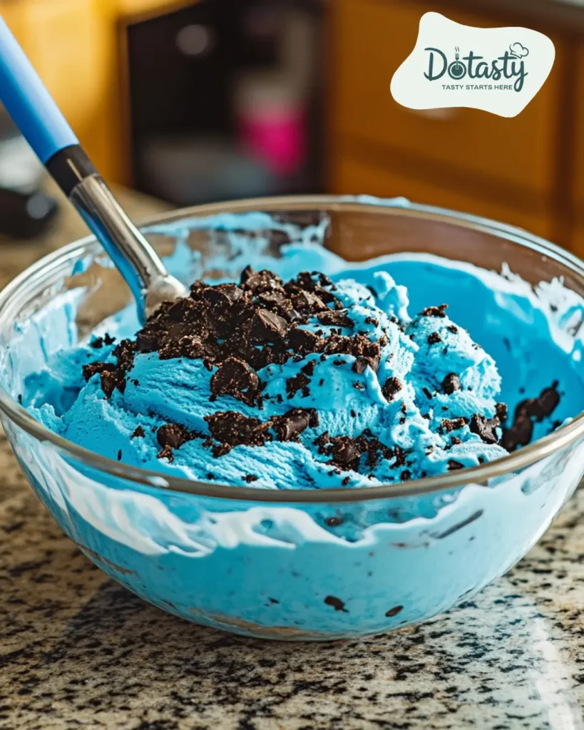 Folding crushed cookies into bright blue ice cream mix.