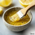 Lemon Pepper Sauce Recipe in a small bowl with a brush and lemon wedges